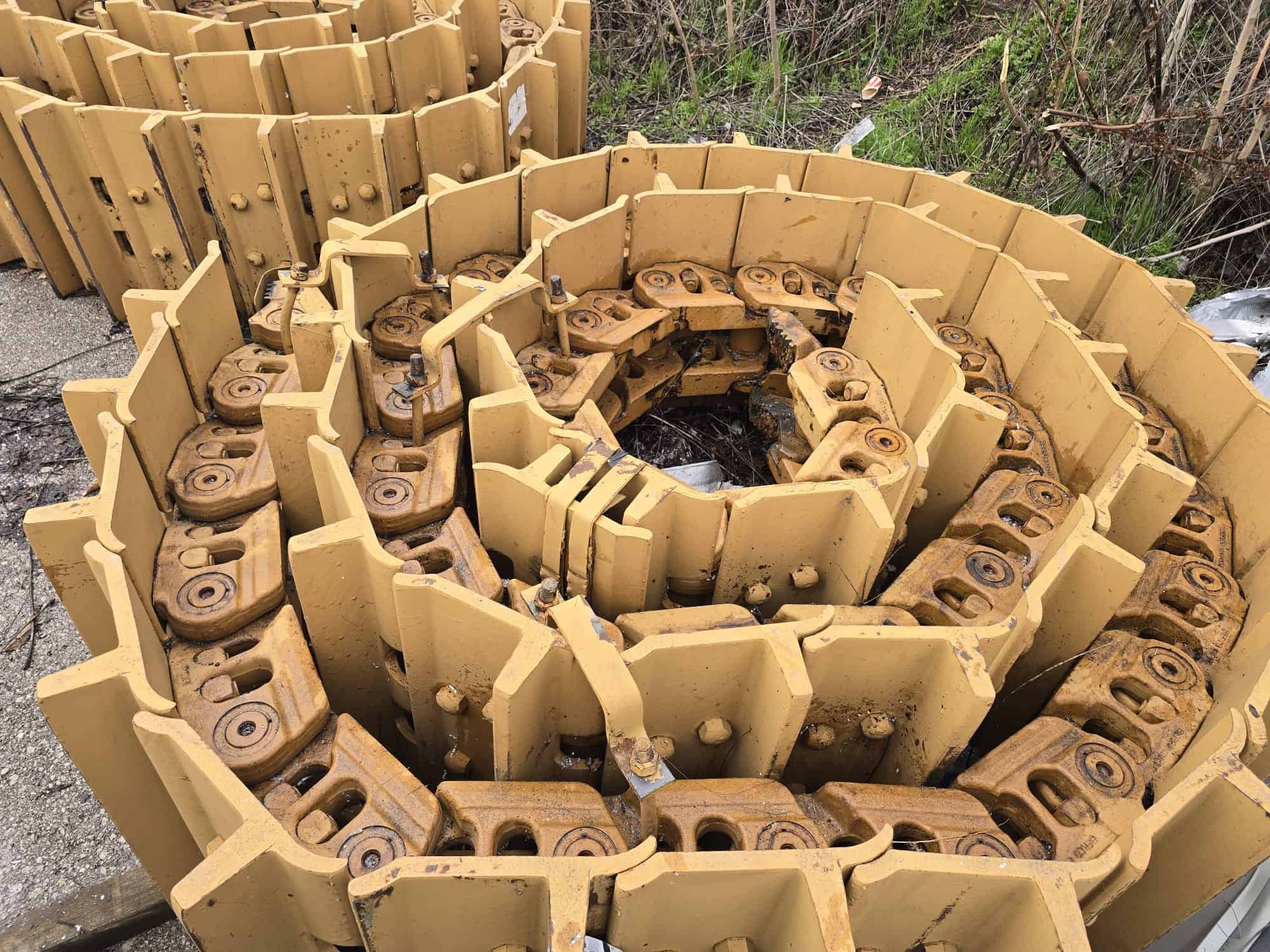 Coiled track links for CAT D9T bulldozer, ready for assembly or repair.