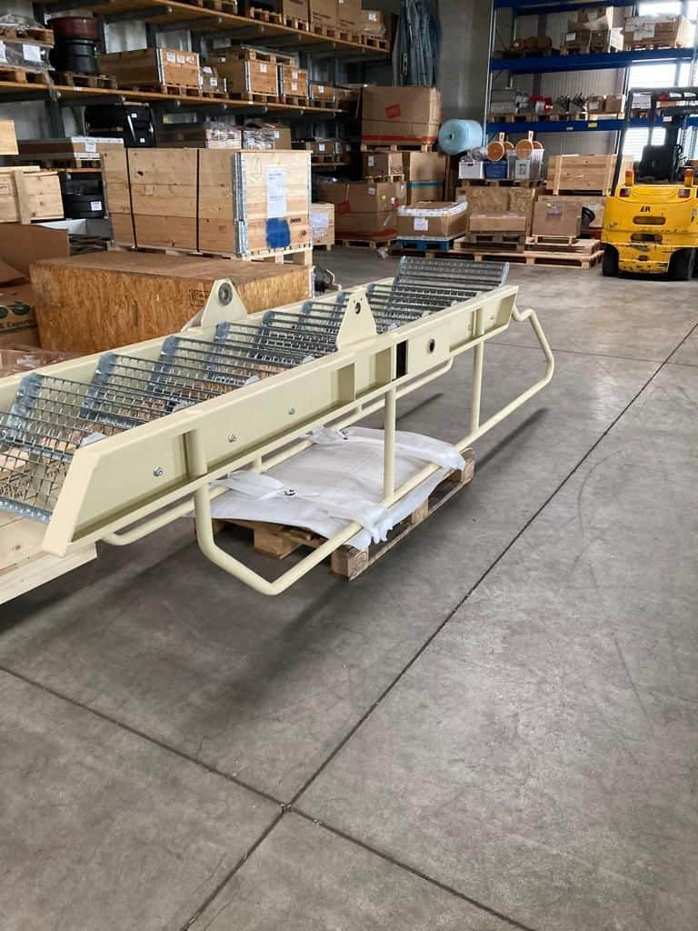 Rettungswagenliege in Lagerhalle mit Holzpaletten und Verpackungsmaterial.