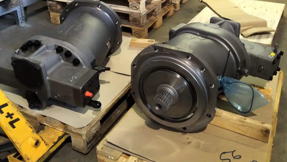 Motoren und Antriebskomponenten auf Paletten in Werkstattumgebung.